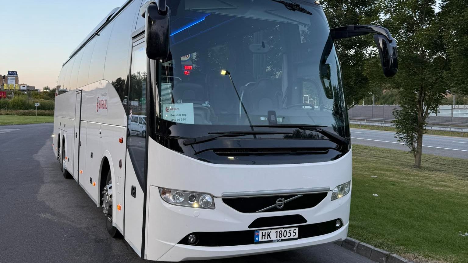 Hvit, moderne turbuss parkert utendørs.